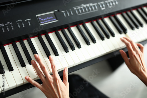 Beautiful female hands lie on a digital piano