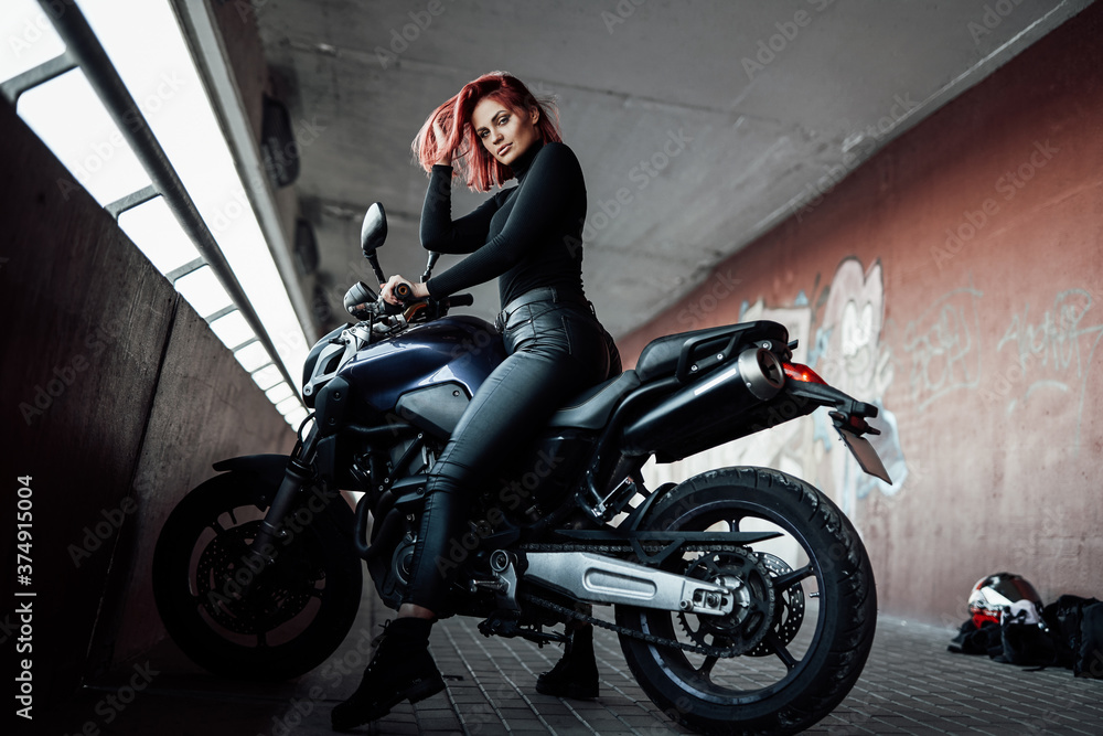 An attractive girl with red hairs sitting on her urban bike