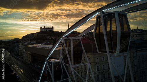 Photography Bratislava ferris wheel detail at sunset with castle and yellow clouds in backgr