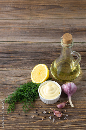 Mayonnaise sauce with garlic, egg, oil and herbs on wooden background