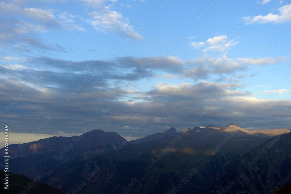 Silhouettes of mountains in the evening haze. Mountain ranges at sunset. Dusk. Silhouettes of mountains in the evening haze. Mountain ranges at sunset. Dusk.