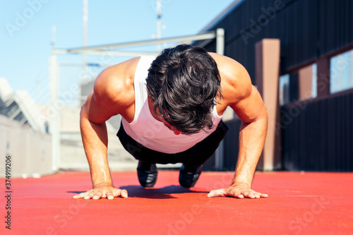 фотографія sporty man doing push ups on a red floor