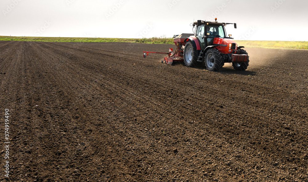 Farmer with tractor seeding crops at field Farmer with tractor seeding crops at field
