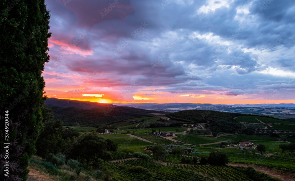 Fototapeta premium Spektakularny zachód słońca w Montalcino w Toskanii we Włoszech z winnicami i farmami w tle