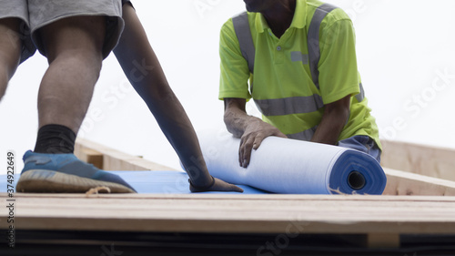 Workers lay an insulating layer of non-woven fabric on the roof.