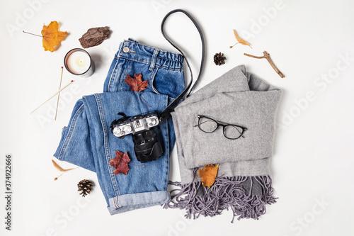 Feminine clothing, camera and yellow leaves on white table photo