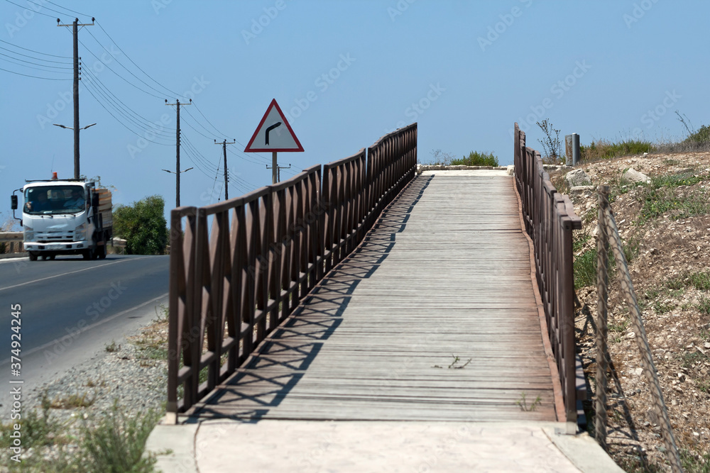 wooden footbridge in the mountains near asphalt road