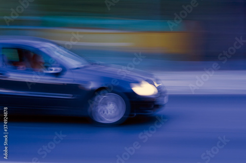 Blurred blue car moving fast along night road  © Olga