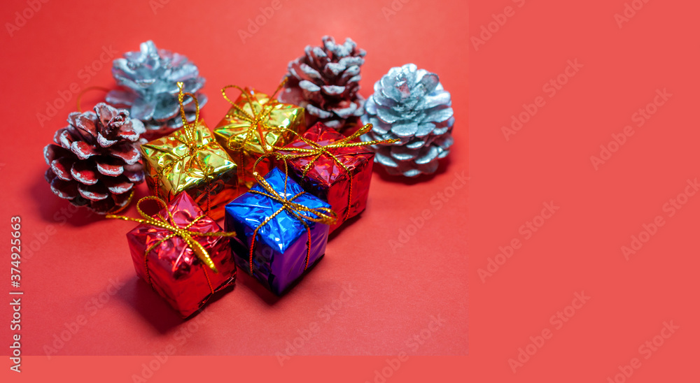 Gifts and pine cones on a red background with copy space. New Year or Christmas card with decor, 2021