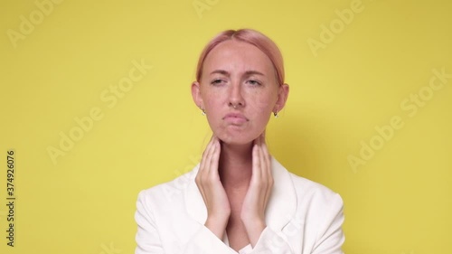 Young caucasian woman checking thyroid gland on yellow background photo