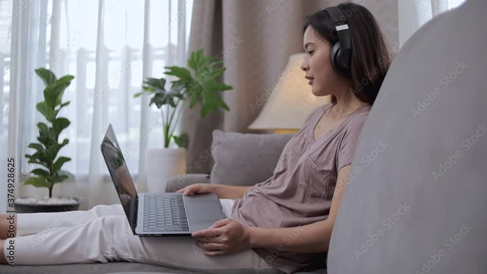 Beautiful asian woman wearing headphones and using laptop computer for working and listning music. Relax and working at home. Beautiful asian woman wearing headphones and using laptop computer for working and listning music. Relax and working at home.