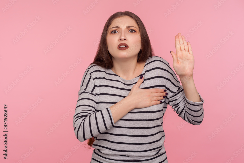 I swear! Portrait of very responsible and honest woman in striped sweatshirt giving promise, making solemn vow in ceremonial tradition with raised hand. indoor studio shot isolated on pink background I swear! Portrait of very responsible and honest woman in striped sweatshirt giving promise, making solemn vow in ceremonial tradition with raised hand. indoor studio shot isolated on pink background