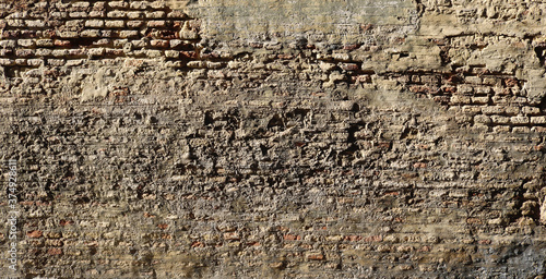destroyed rough and ancient wall background with layers of gray cement and bricks from an abandoned building
