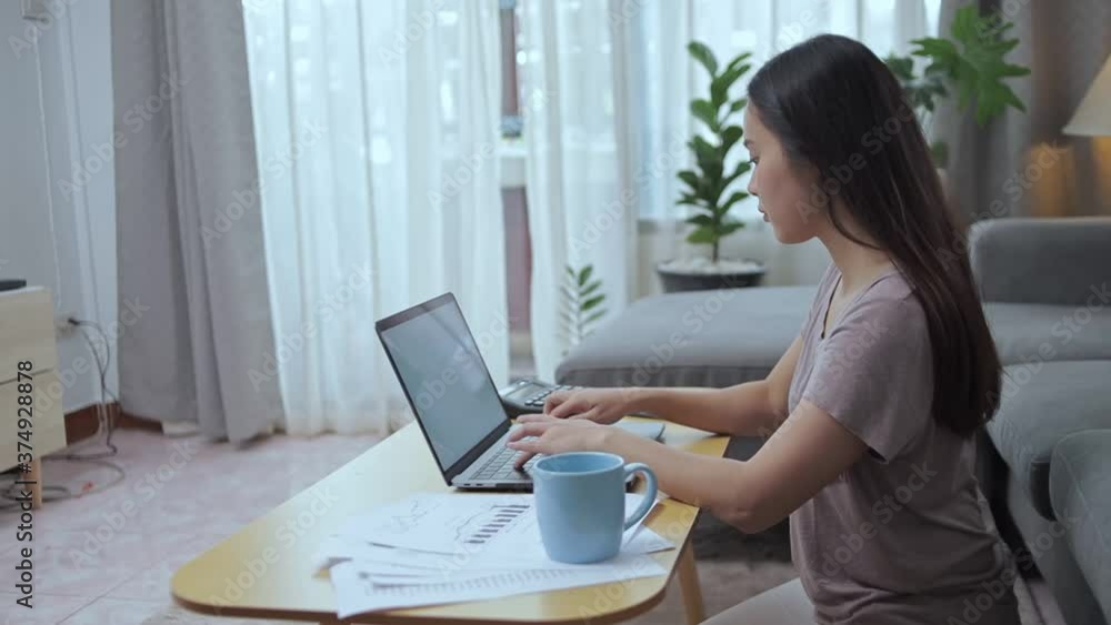 woman busy working on laptop and use mobile phone for talking with customer and short note in a book at home. woman busy working on laptop and use mobile phone for talking with customer and short note in a book at home.