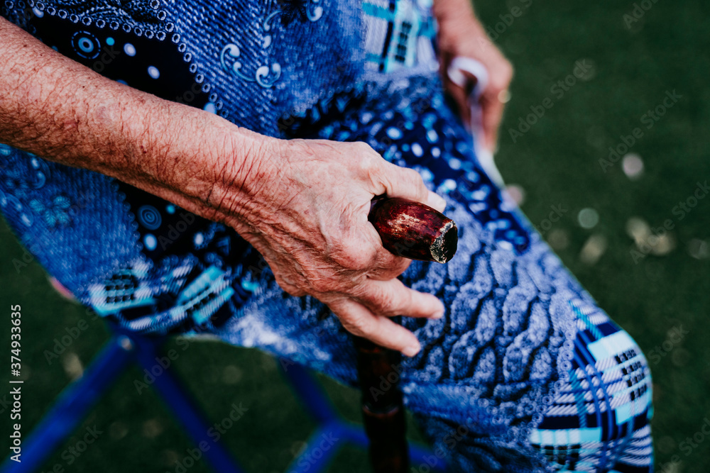 close up of old lady hands holding a stick outdoors
