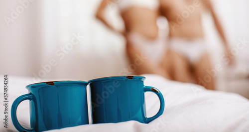 Cups on the bed. Couple in love, blurred background. Love couple. Hotel room. Bed. 