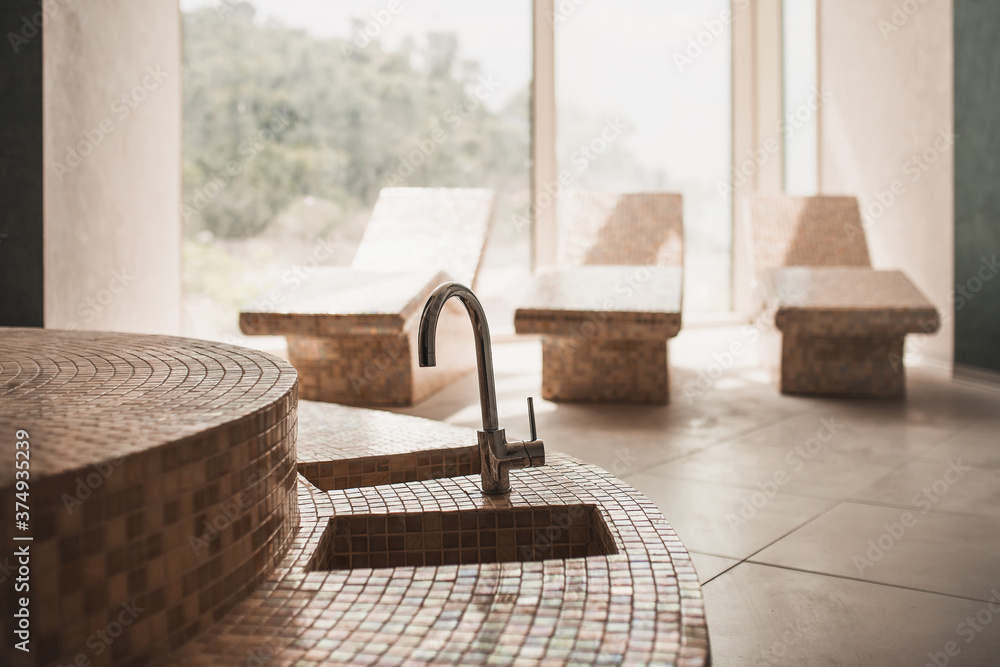 Sauna interior with beaded tiles and a foot wash tap - loungers for relaxation Sauna interior with beaded tiles and a foot wash tap - loungers for relaxation