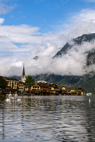Hallstatt, Austria. View to Hallstattersee Lake and Alps mountains summits. Ancient houses at lake banks with chapel. Tourism in Austria. The Alps are a popular tourist destination.  Europe. © notistia
