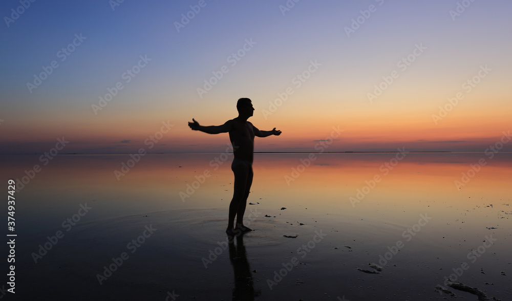 man stands on sea coast on sunset background