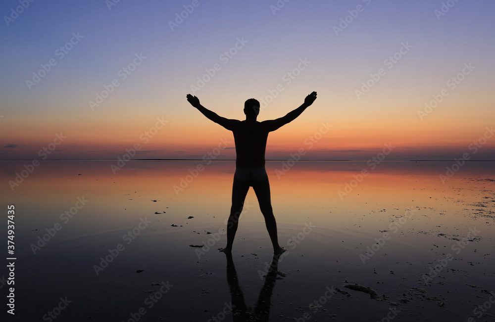man stands in the water on sunset background