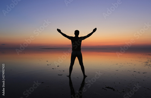 man stands in the water on sunset background