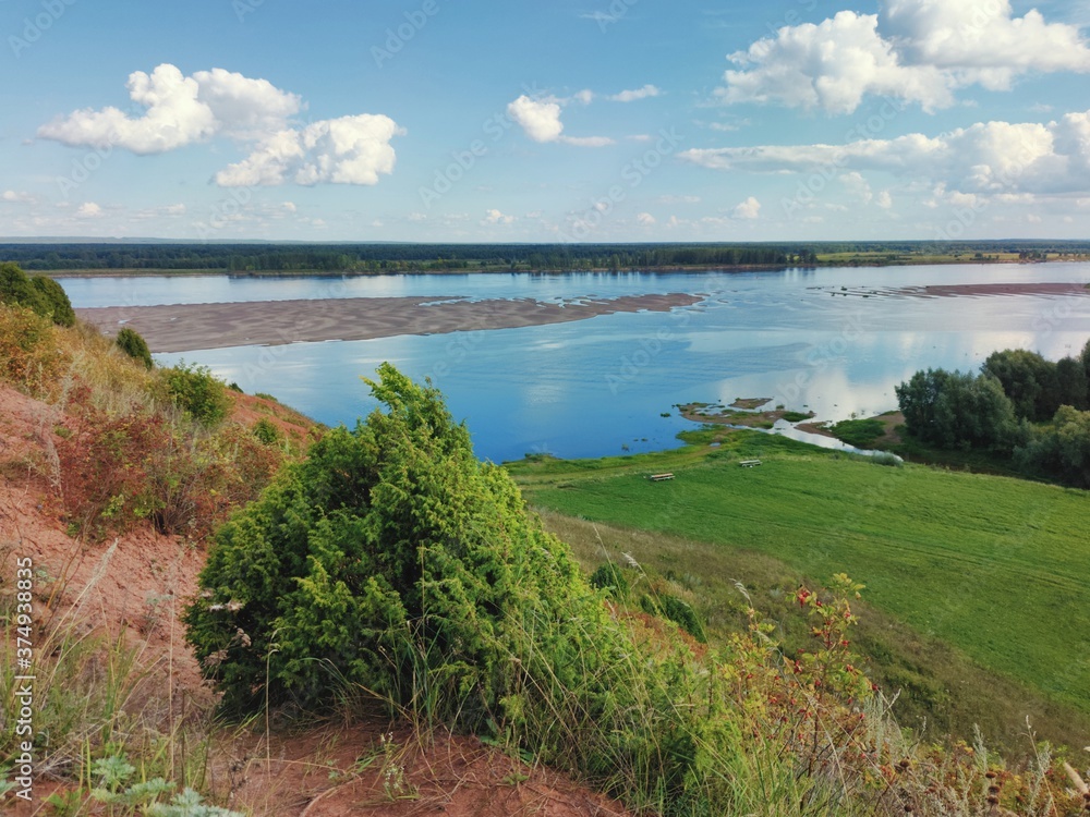 Obraz premium mountainside on the background of a river with a sandy island and a blue sky with clouds