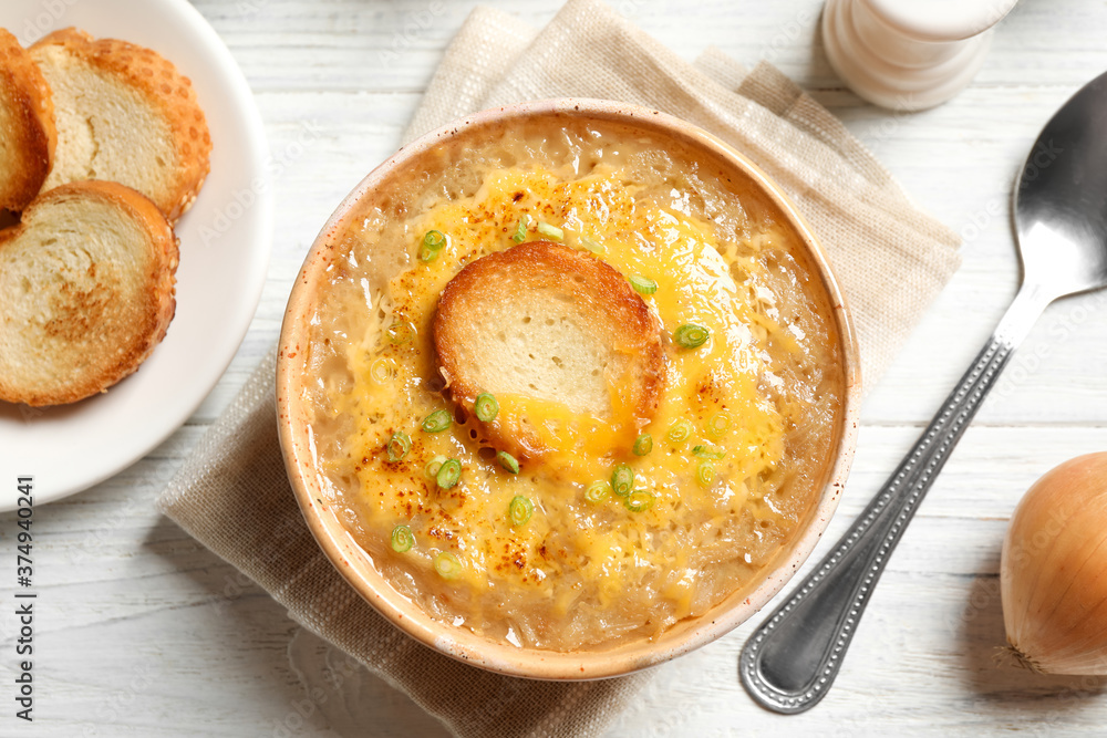 Tasty homemade french onion soup served on white wooden table, flat lay Tasty homemade french onion soup served on white wooden table, flat lay