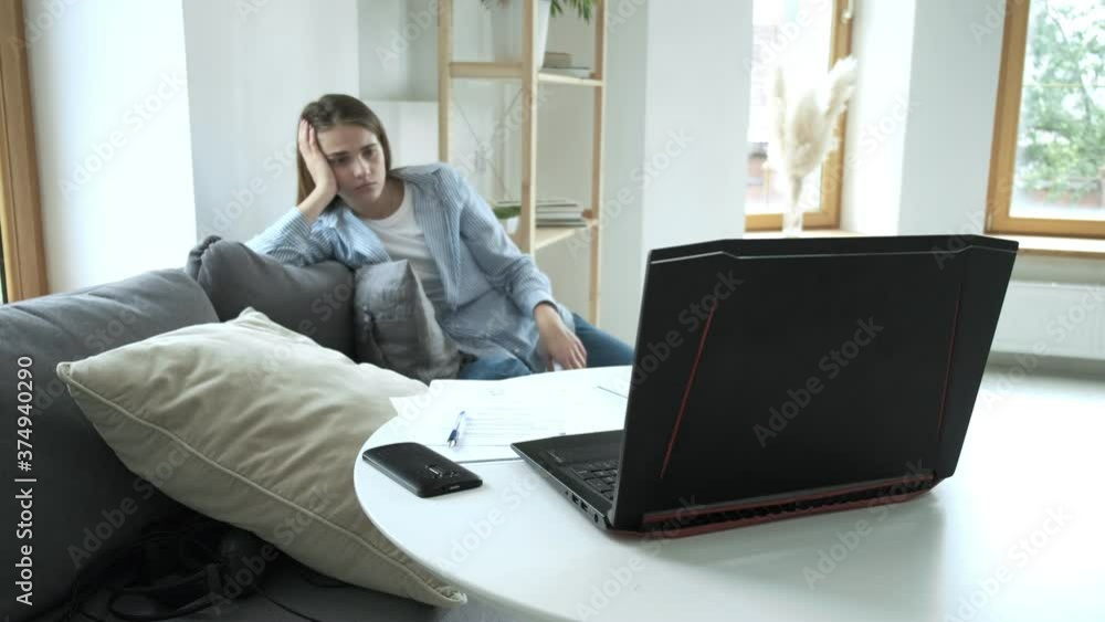 freelancer girl tired of her work sits on couch and throws crumpled paper into laptops screen on table. Attractive young caucasian woman sick of working on computer at home office. freelancer girl tired of her work sits on couch and throws crumpled paper into laptops screen on table. Attractive young caucasian woman sick of working on computer at home office.