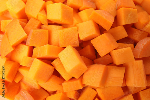 Cubes of fresh ripe carrots as background, top view