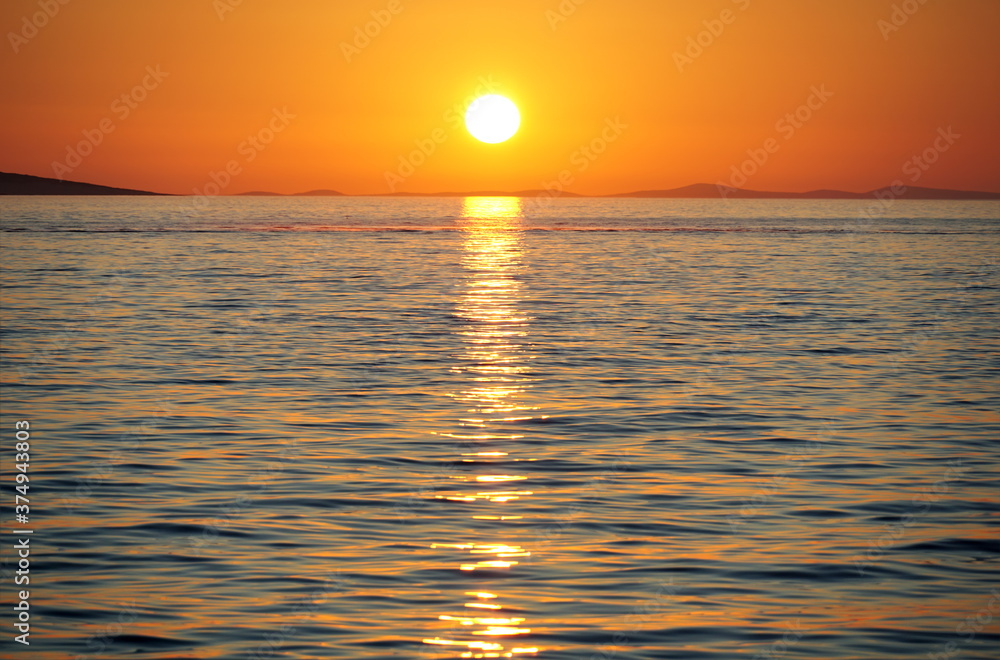 Beautiful orange sundown above wavy blue sea water