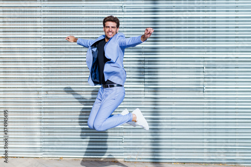 Young man wearing a suit jumping outdoors