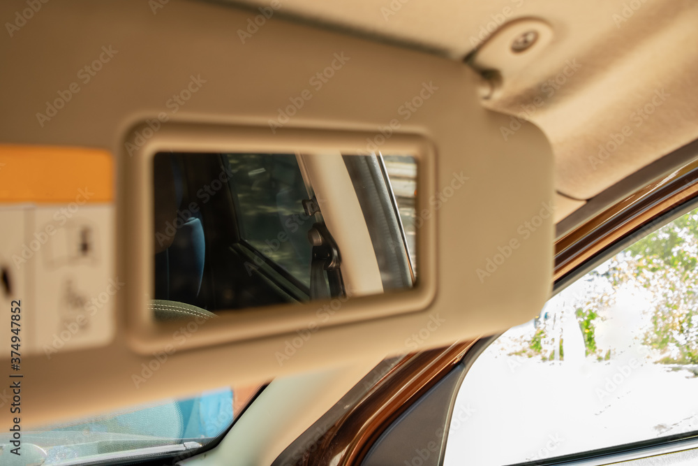 A mirror for a passenger in a brown car in a sunny summer day, blurred background A mirror for a passenger in a brown car in a sunny summer day, blurred background