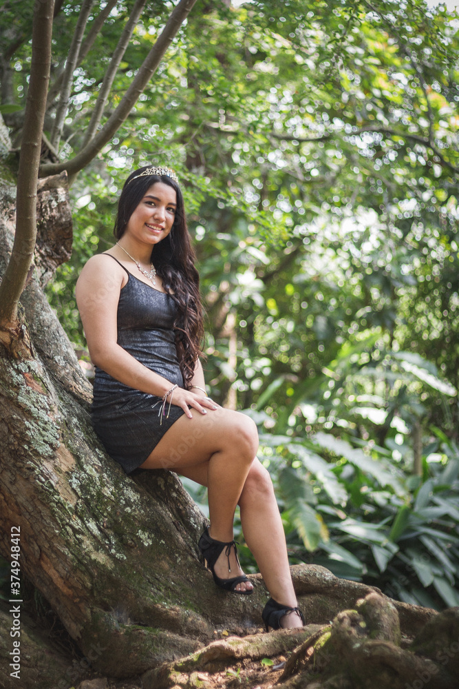 Hermosa mujer joven morena con un vestido de color negro sonriendo en un entorno con mucha naturaleza Hermosa mujer joven morena con un vestido de color negro sonriendo en un entorno con mucha naturaleza
