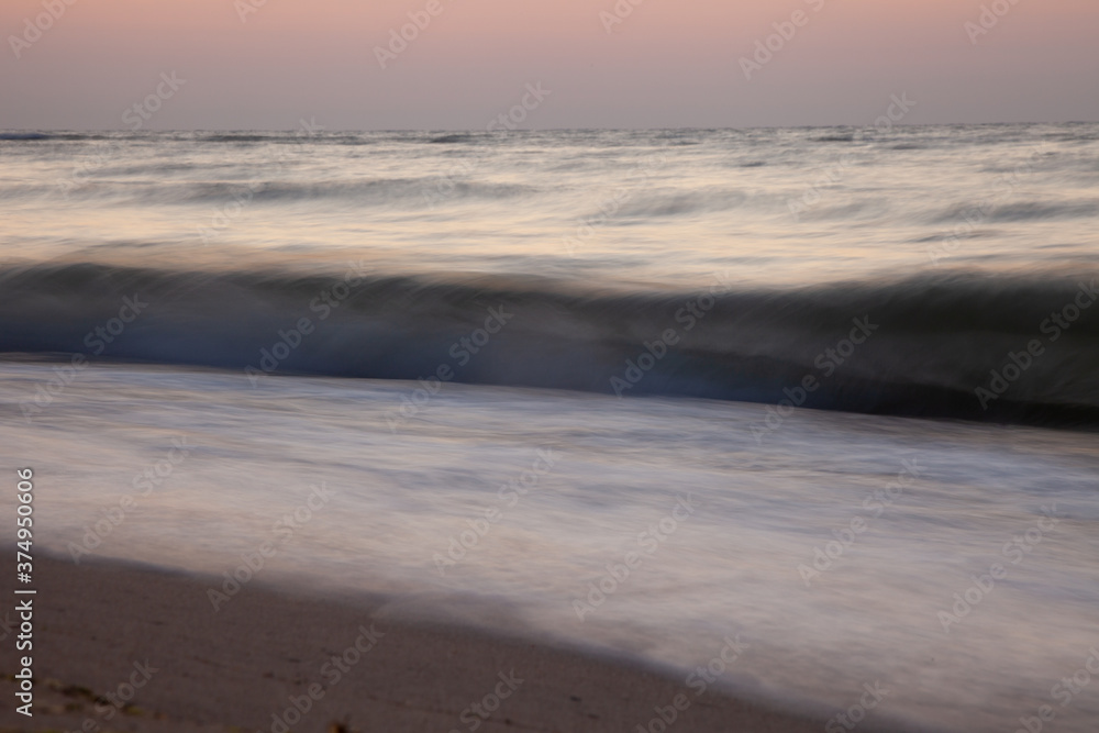 Seascape. Waves and surf. Sunset and dawn at sea. Calm on the ocean. Beautiful sky and clouds illuminated by the sun. Natural background. Summer time.