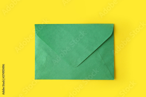 Green paper envelope on yellow background, top view