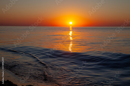 Seascape. Waves and surf. Sunset and dawn at sea. Calm on the ocean. Beautiful sky and clouds illuminated by the sun. Natural background. Summer time.