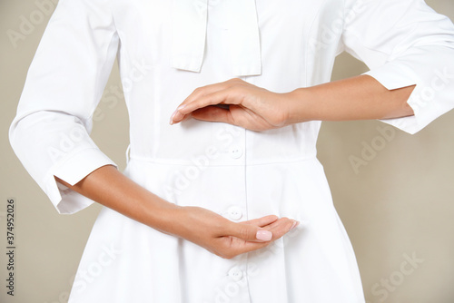 Close up cropped photo of woman s slim stomach with her hands showing a balance in microflora in a white robe.
