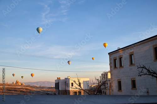 Cappadocia, Turkey - December 20, 2019: Hot air balloons flying in blue sky with white clouds over homes of city Goreme at morning during sinrise, Great interesting attraction for tourists