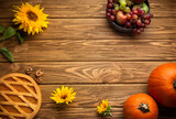 Thanksgiving seasonal background, rustic wooden with autumn decoration: pumpkins, pie, sunflowers, apples and grape. Celebration Thanksgiving or fall concept, space for text, top view.
