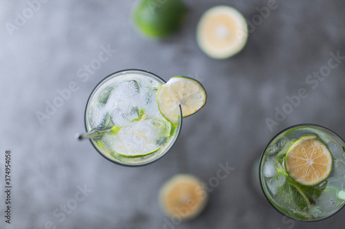 Flat lay top view of cold refreshing beverage with sliced lime ripes and ice reverse light image in studio with white illuminated background
