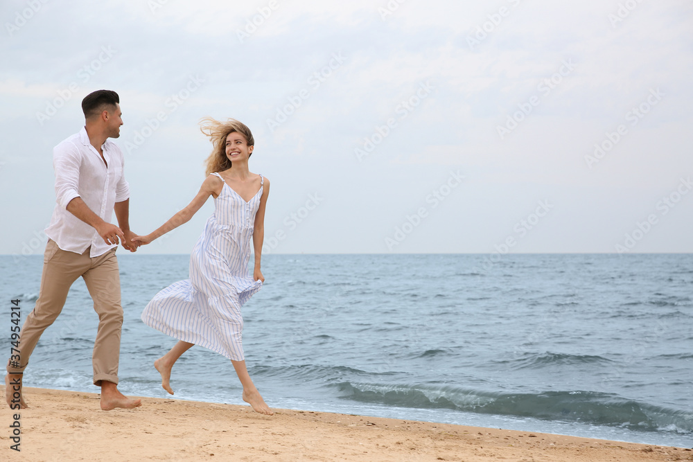 Happy couple running on beach, space for text. Romantic walk Happy couple running on beach, space for text. Romantic walk