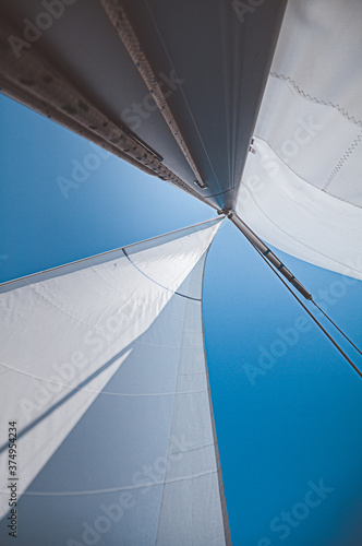 Sailing ship yacht with white sails in sky. Luxury boat on ocean with wind in sails against sky.