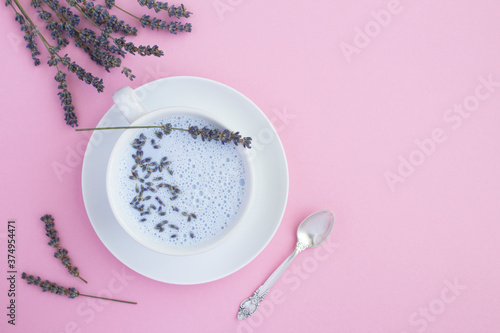 Top view of lavender moon milk in the white cup on the pink surface. Copy space.