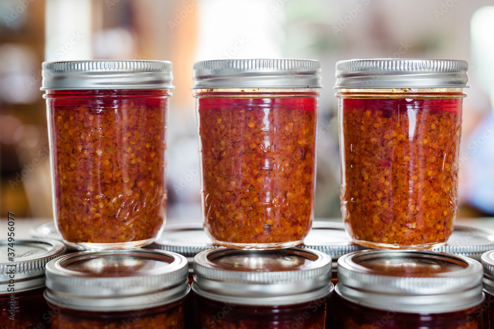 Jars of Thai Chili Paste / Chili Sauce on a kitchen counter. This spicy chili jam is called chili oil, or Naam Prik Phao and Vietnamese Lemongrass Chili Garlic Sate ( Jars of Thai Chili Paste / Chili Sauce on a kitchen counter. This spicy chili jam is called chili oil, or Naam Prik Phao and Vietnamese Lemongrass Chili Garlic Sate (