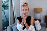 Portrait of sexy blonde woman in body suit and white shirt with pink beautiful lips holding cigar in living room at home.