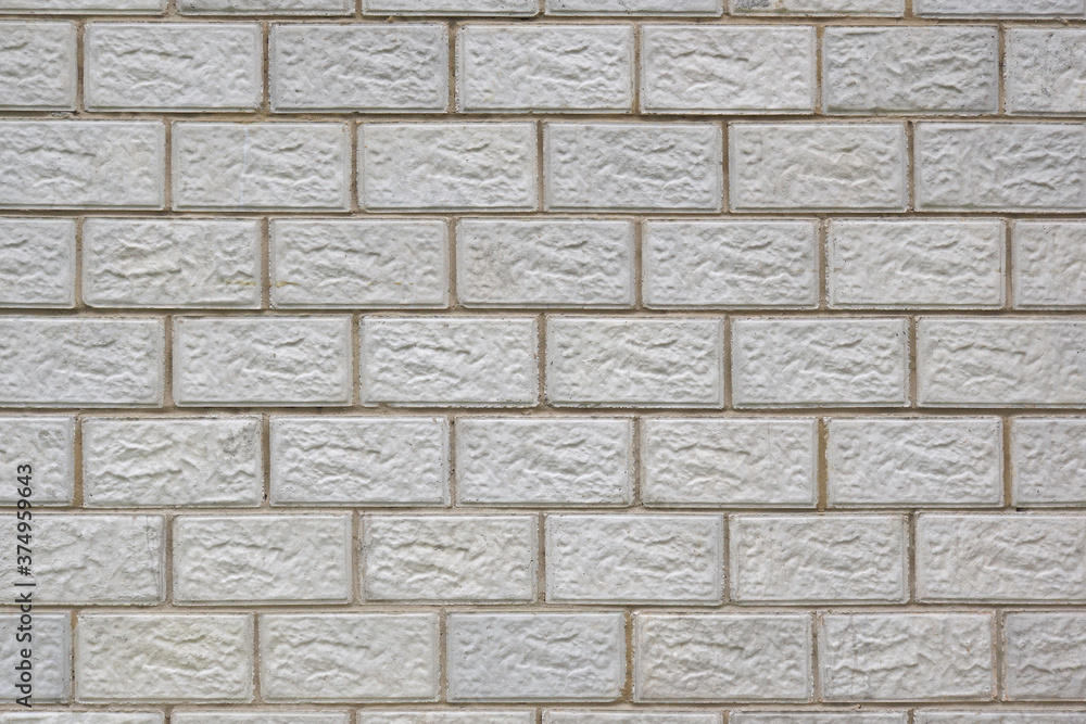 Obraz premium The wall of the house is made of gray concrete blocks. Background or wallpaper. The seams form a pattern similar to brickwork. Light backdrop on the topic of housing construction and renovation