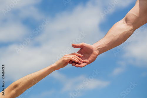 Giving a helping hand. Hands of man and woman on blue sky background. Lending a helping hand. Solidarity, compassion, and charity, rescue