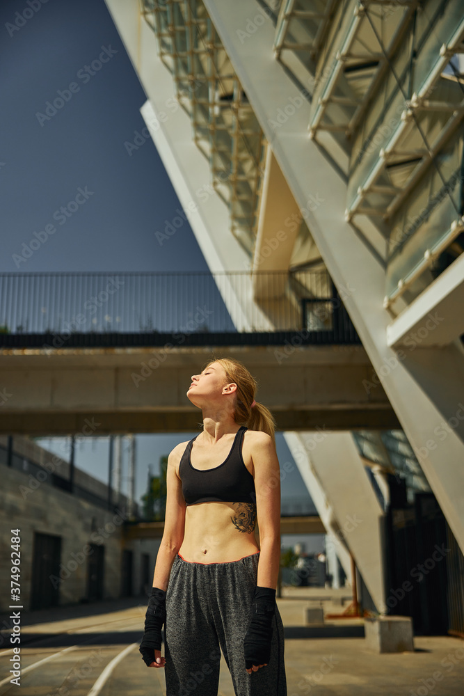 Obraz premium Sportive beautiful female enjoying sunny rays after training outdoor