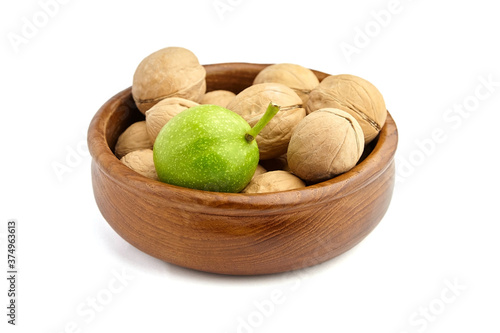 Ripe and green walnuts in bowl isolated on white background