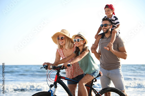 Happy family with bicycle on beach near sea © New Africa